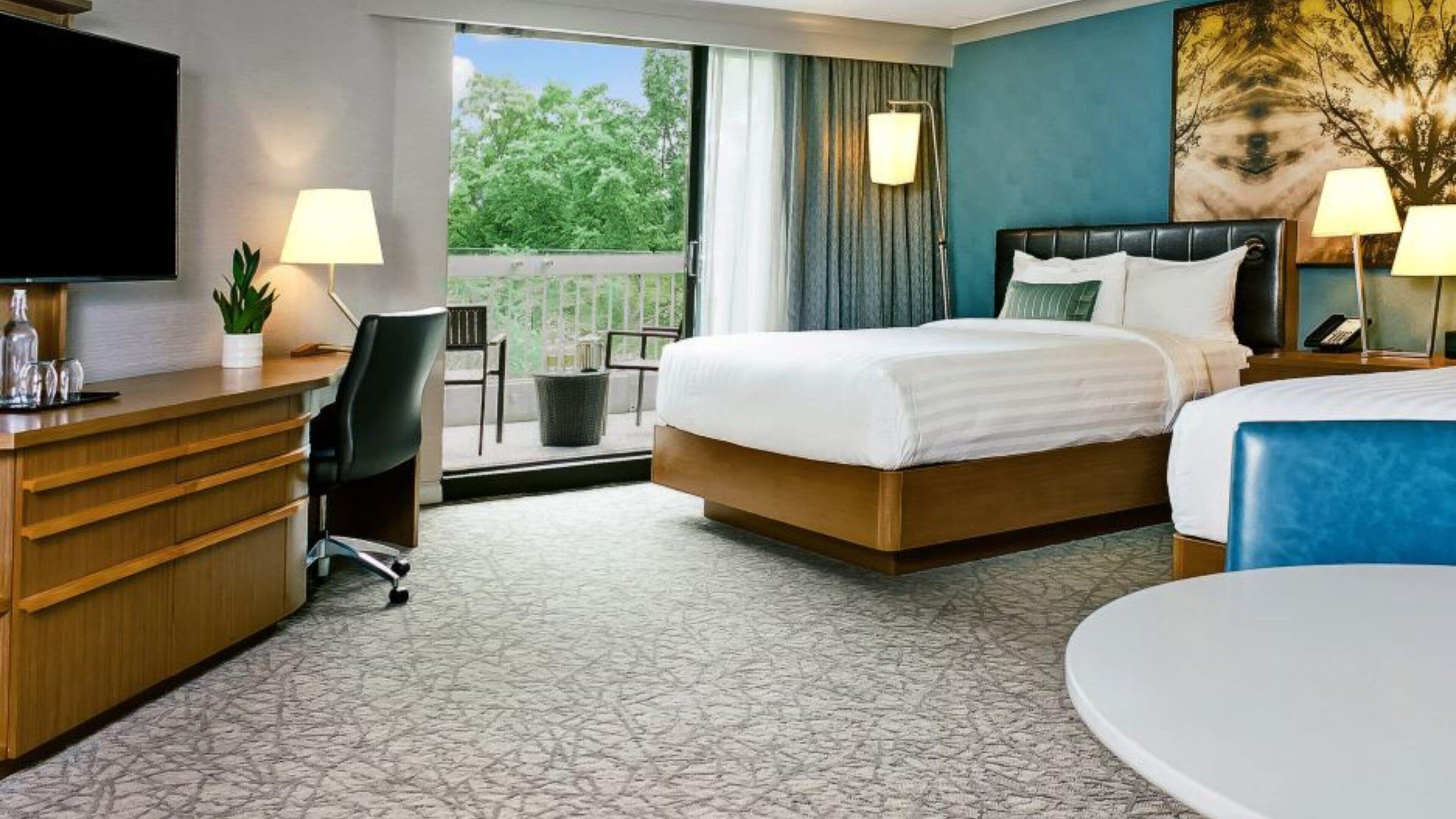 A hotel room with a bed, desk, chair, and a TV.