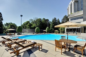 Una piscina al aire libre de temporada, sombrillas