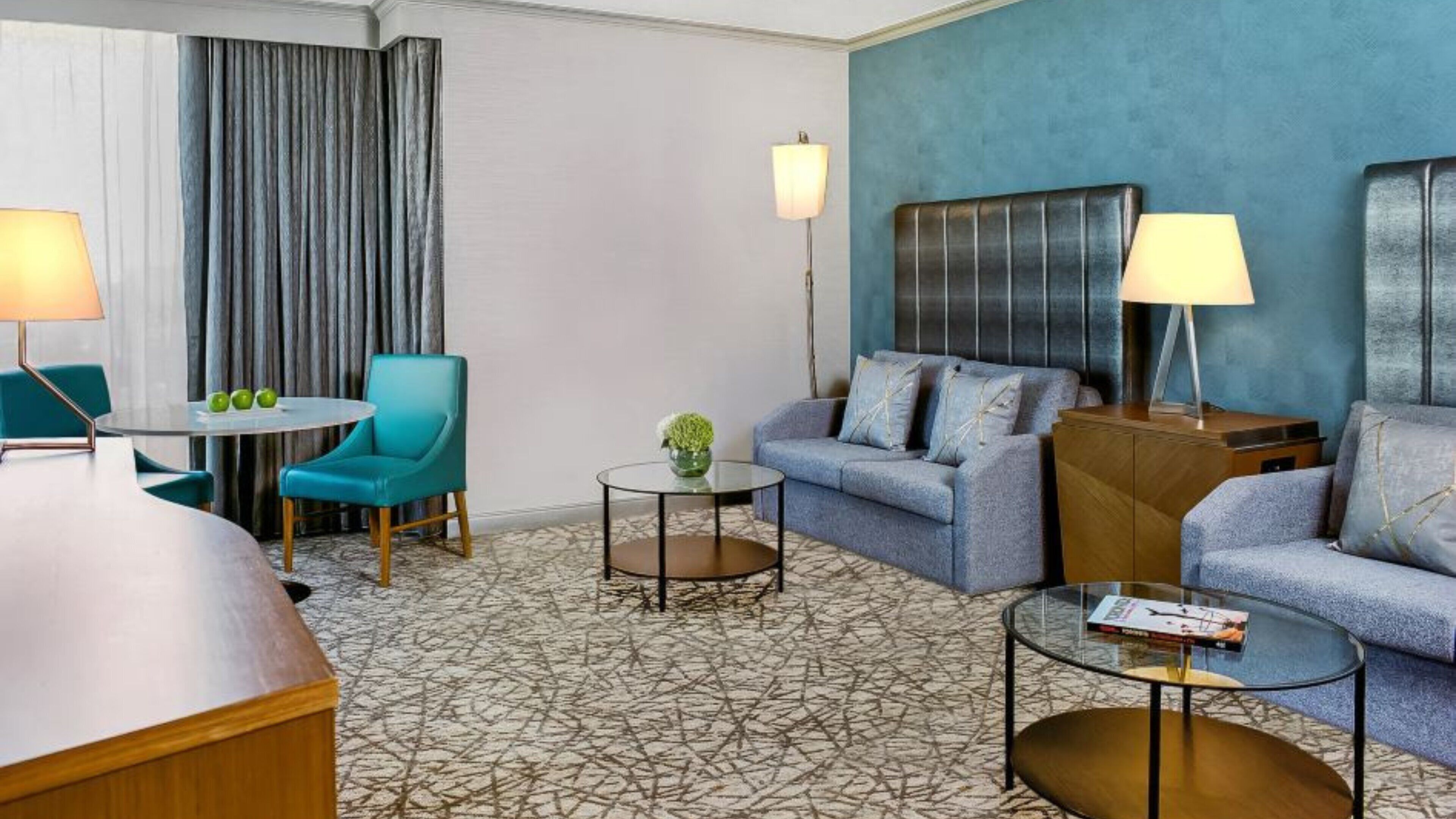 Une chambre d’hôtel équipée d’un canapé, de fauteuils, d’une table à manger et d’une petite table basse.