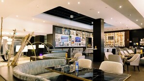 A modern hotel lobby with seating areas, a wall of framed pictures, and a bar area. - Crowne Plaza Toronto North York by IHG (Toronto)