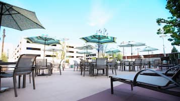 An outdoor seating area with multiple tables and chairs, surrounded by umbrellas.