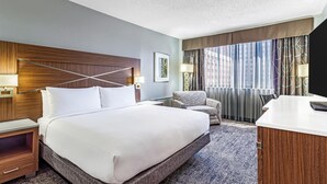 A hotel room with a large bed, a desk, a chair, and a view of the city through the window. - DoubleTree by Hilton Milwaukee Downtown (Milwaukee)