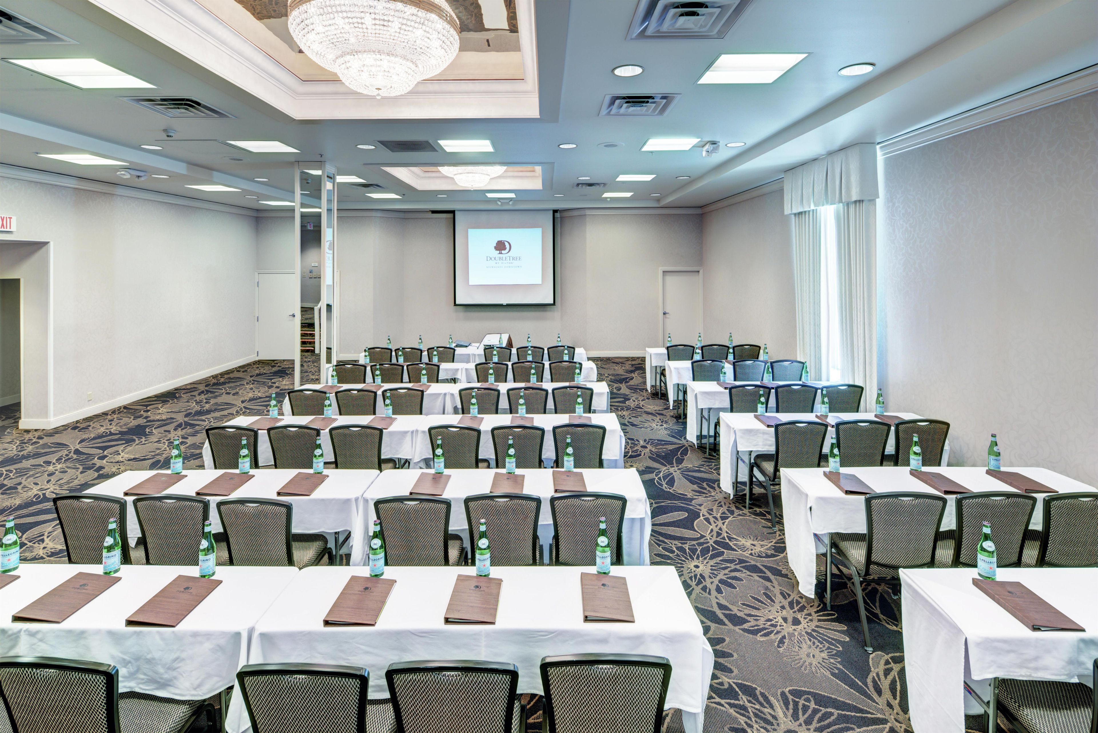 A conference room with multiple tables, chairs, and a projector screen.