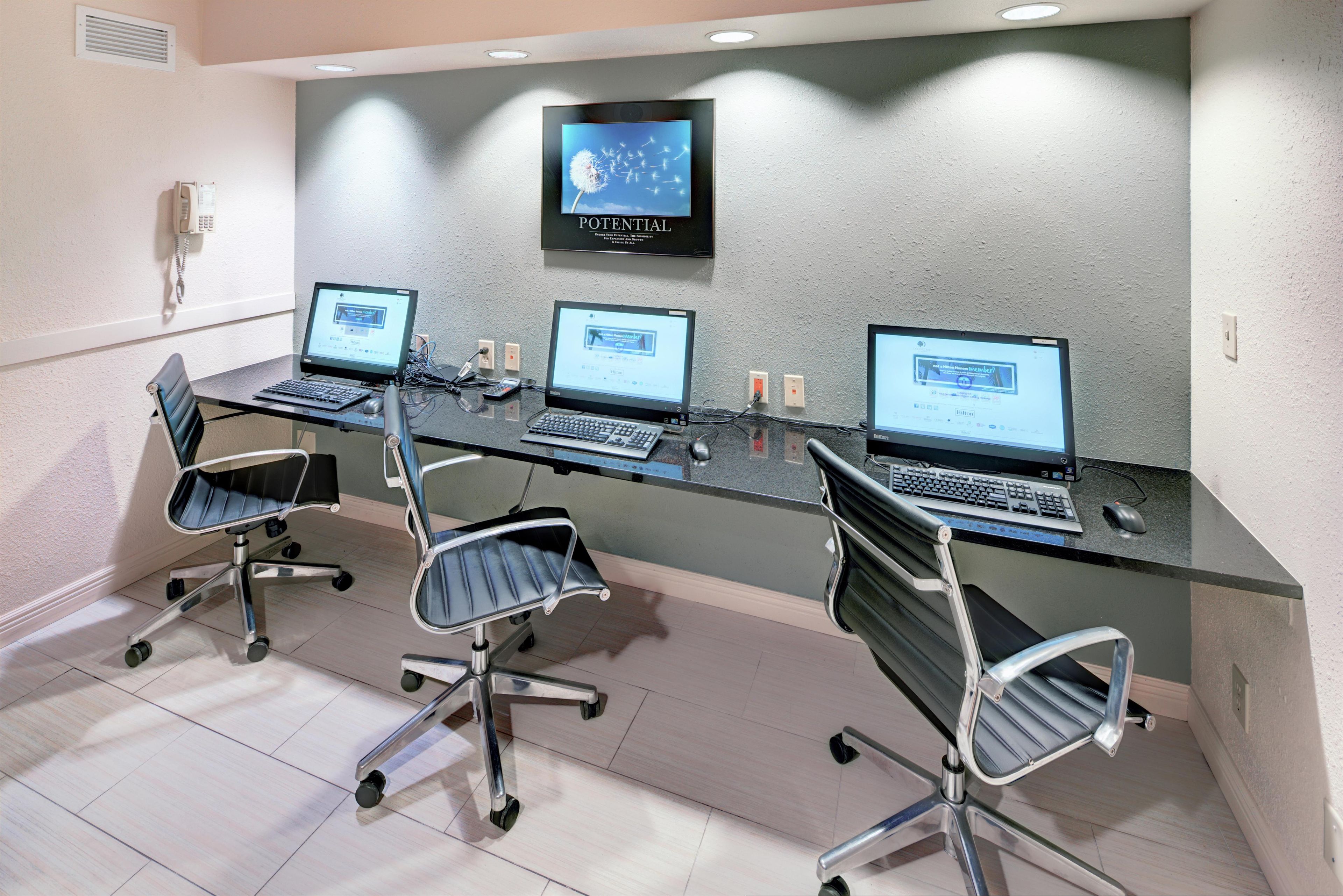 A conference room with three desktop computers, two chairs, and a wall-mounted TV displaying a dandelion.