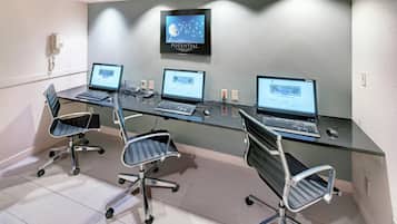 A conference room with three desktop computers, two chairs, and a wall-mounted TV displaying a dandelion.