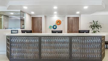 A reception desk with a modern design, a sign indicating it's Hilton, and a decorative wall with circular elements.