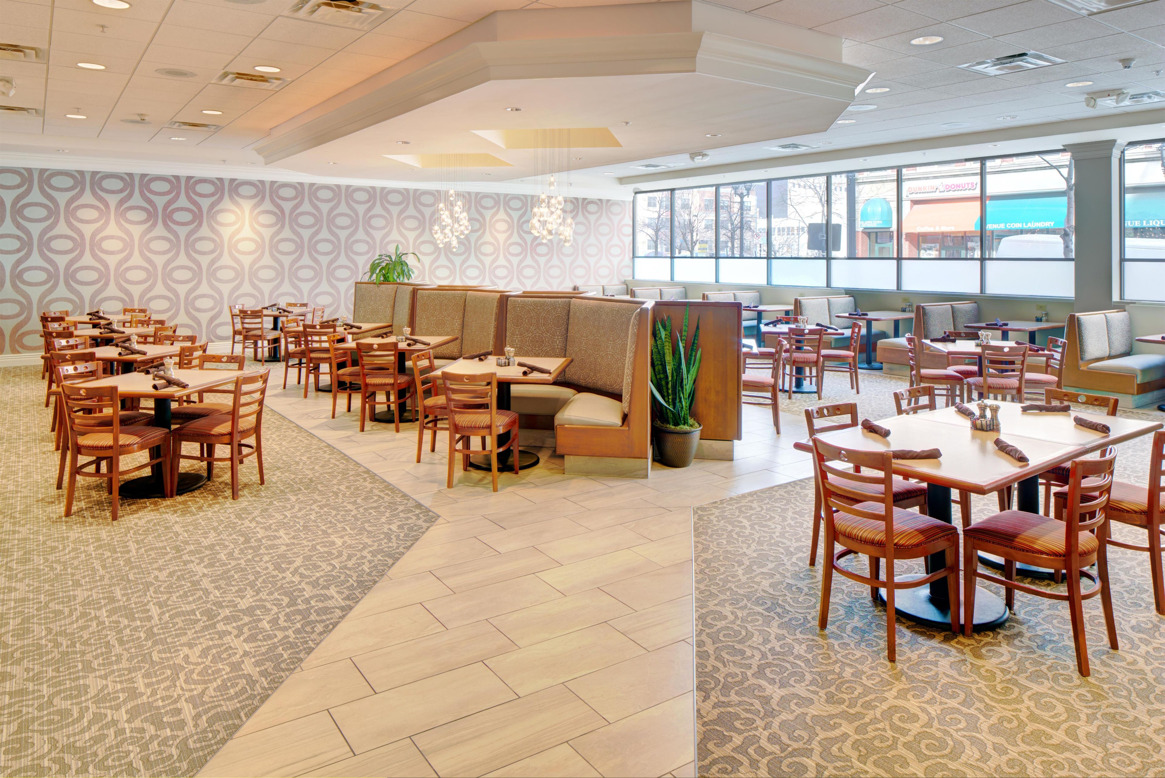 A spacious restaurant with high ceilings, patterned wallpaper, and a variety of seating options including booths and tables.