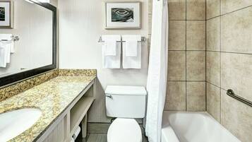 Un baño con encimera de granito, inodoro, bañera y cortina de ducha.