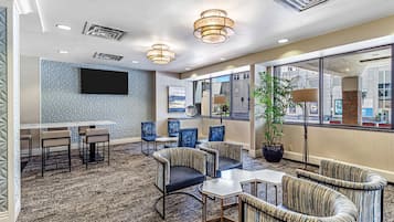 A hotel lobby with a bar, seating area, and large windows.