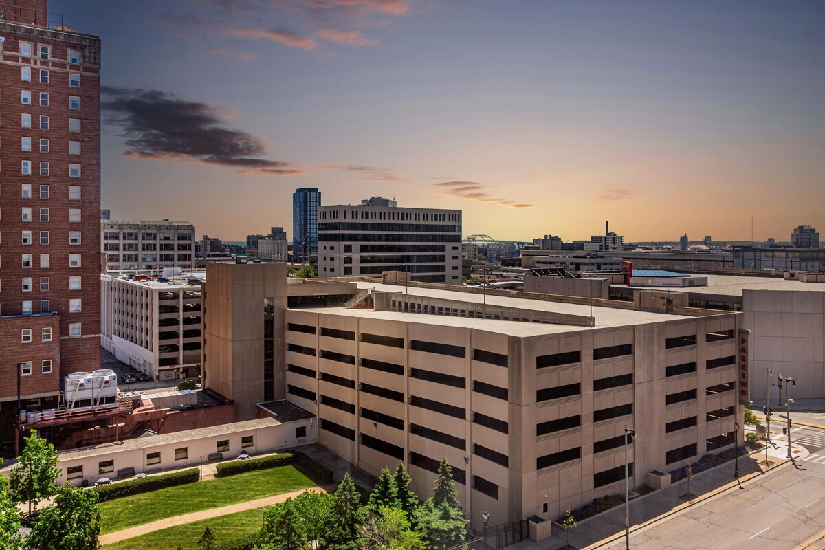 A multi-story parking garage with a flat roof, surrounded by buildings and a clear sky.