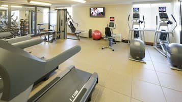 A gym with treadmills, elliptical machines, and a red exercise ball.