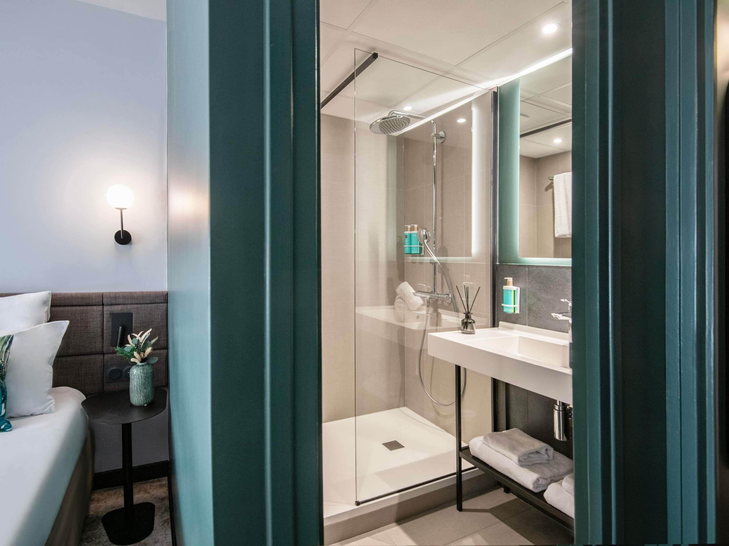 Un baño moderno con cabina de ducha de vidrio, un lavabo blanco y un espejo encima.