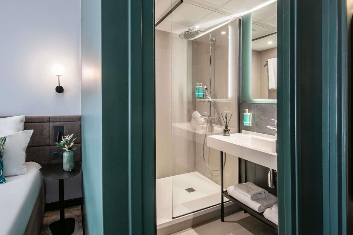 Un baño moderno con cabina de ducha de vidrio, un lavabo blanco y un espejo encima.
