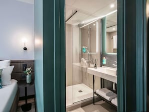 Un baño moderno con cabina de ducha de vidrio, un lavabo blanco y un espejo encima.