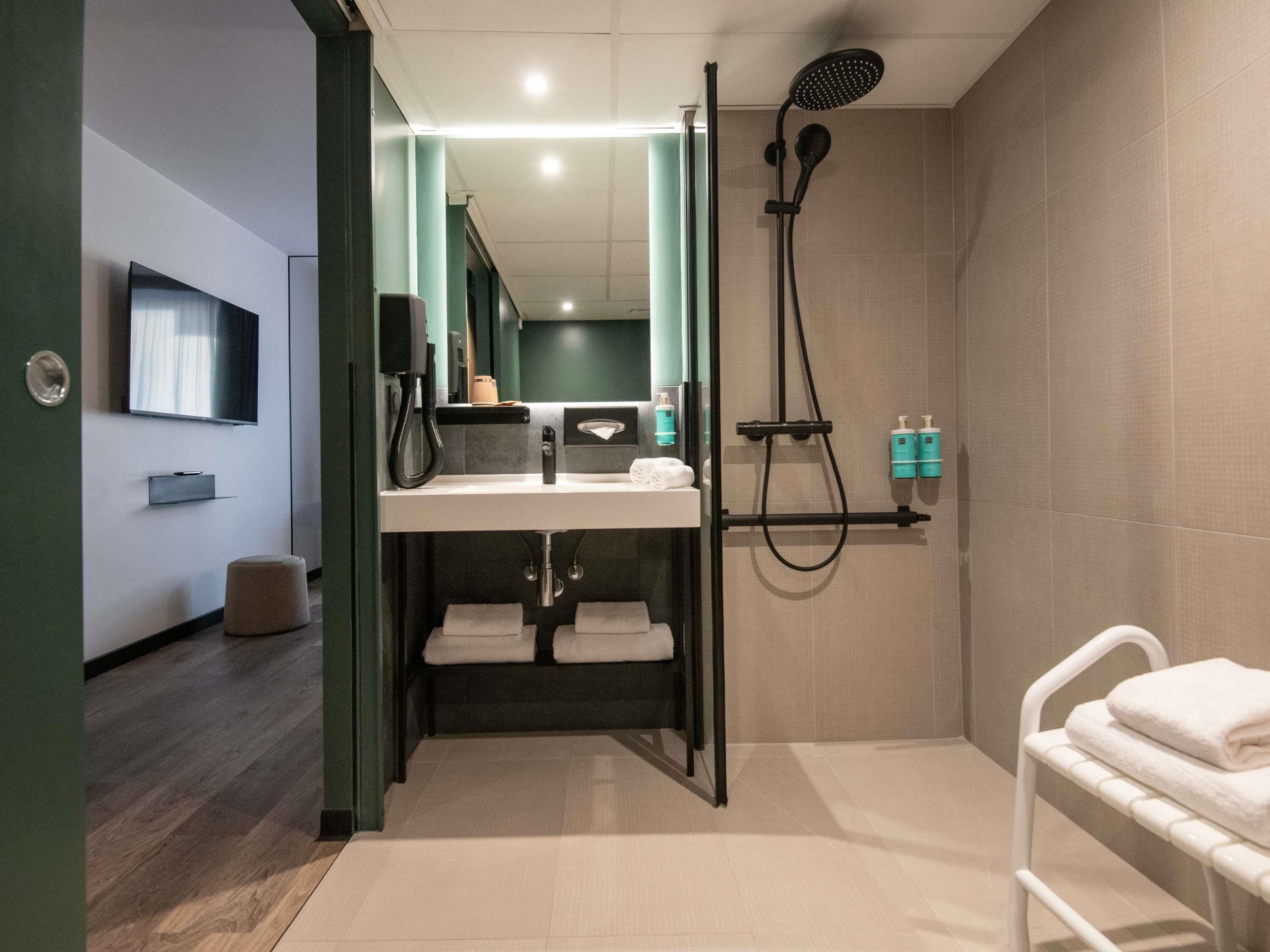 Een moderne badkamer met een douche, een wastafel met spiegel en een handdoekrek.