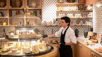 A cheese display with a glass dome, surrounded by wooden shelves with various items.