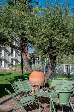 An outdoor seating area with metal chairs and a large terracotta pot. - Novotel Nice Aeroport Cap 3000 (Saint-Laurent-du-Var)