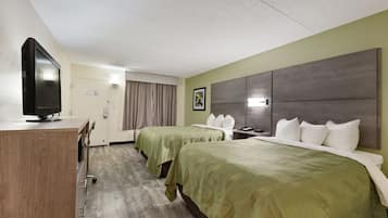 Una habitación de hotel con dos camas, un escritorio, un televisor y un amplio ventanal con cortinas.