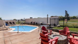 A pool area with a hot tub, red Adirondack chairs, and a fire pit. - La Quinta Inn & Suites by Wyndham Helena (Helena)