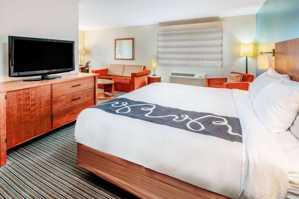 A hotel room with a bed, a television, a desk, and a chair.