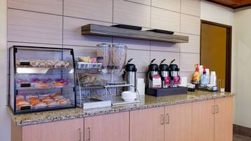 Un comptoir-buffet où l’on sert le petit-déjeuner, avec un présentoir réfrigéré, des machines à café et une variété d’aliments.