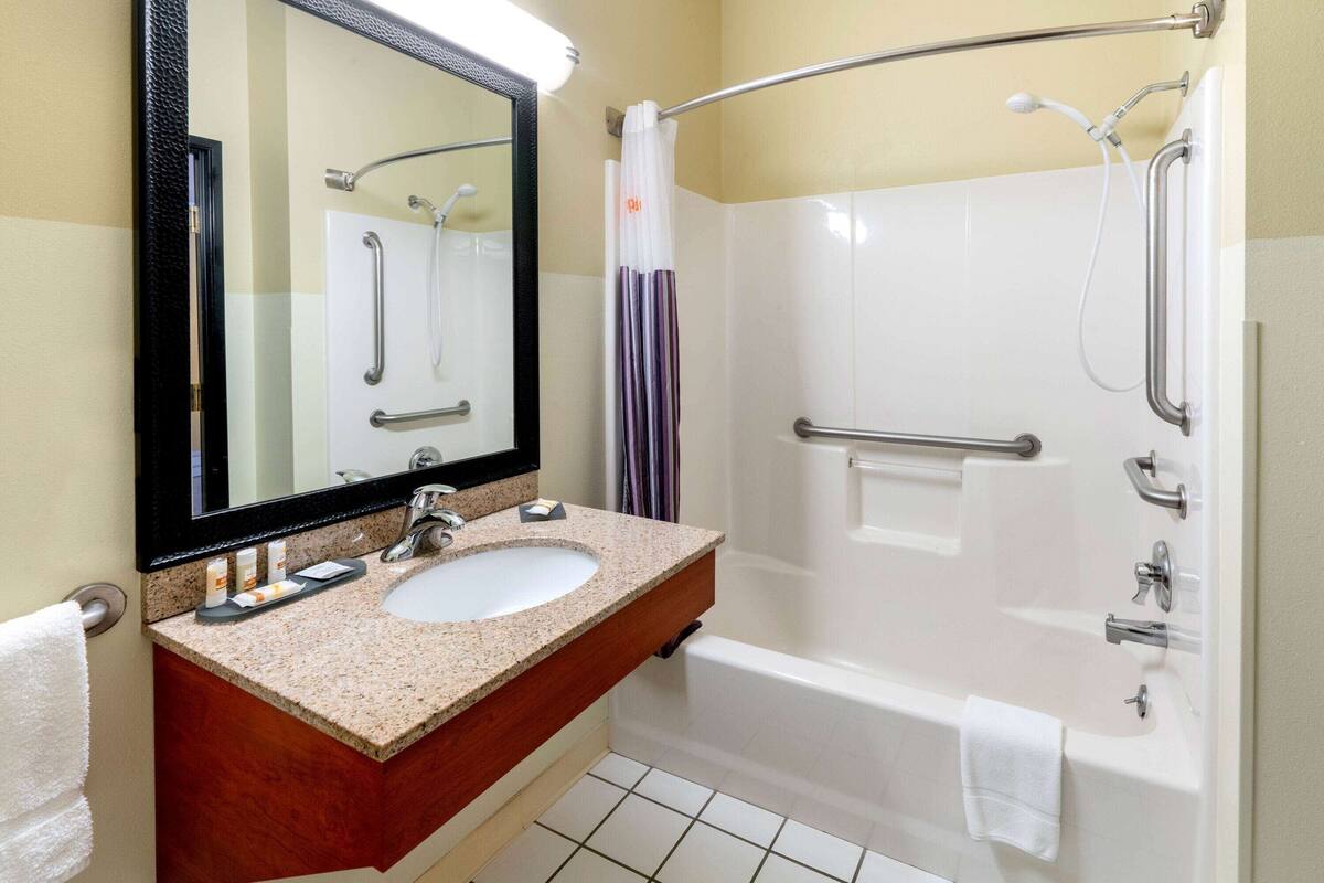 A bathroom with a sink, mirror, and bathtub.