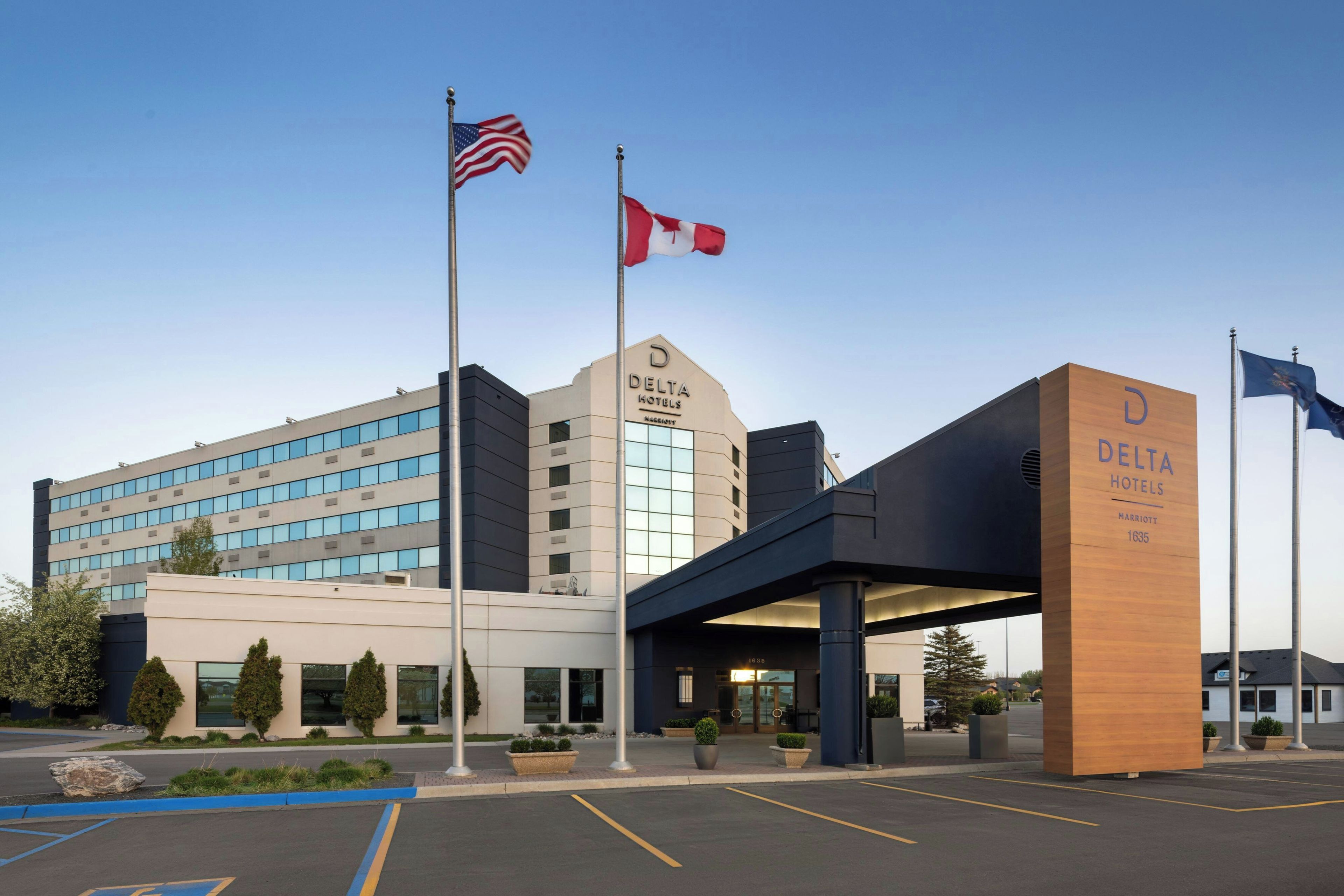A Delta Hotels building with a modern architectural design, featuring a prominent entrance and multiple flags.
