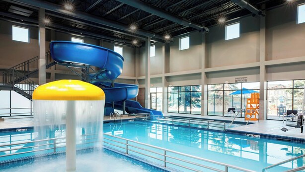 An indoor swimming pool with multiple slides and a water feature.