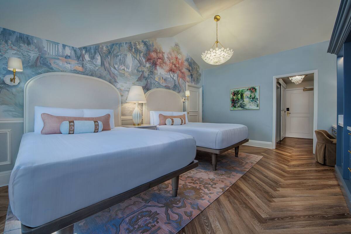 A bedroom with two beds, a large mural, and a herringbone wood floor.