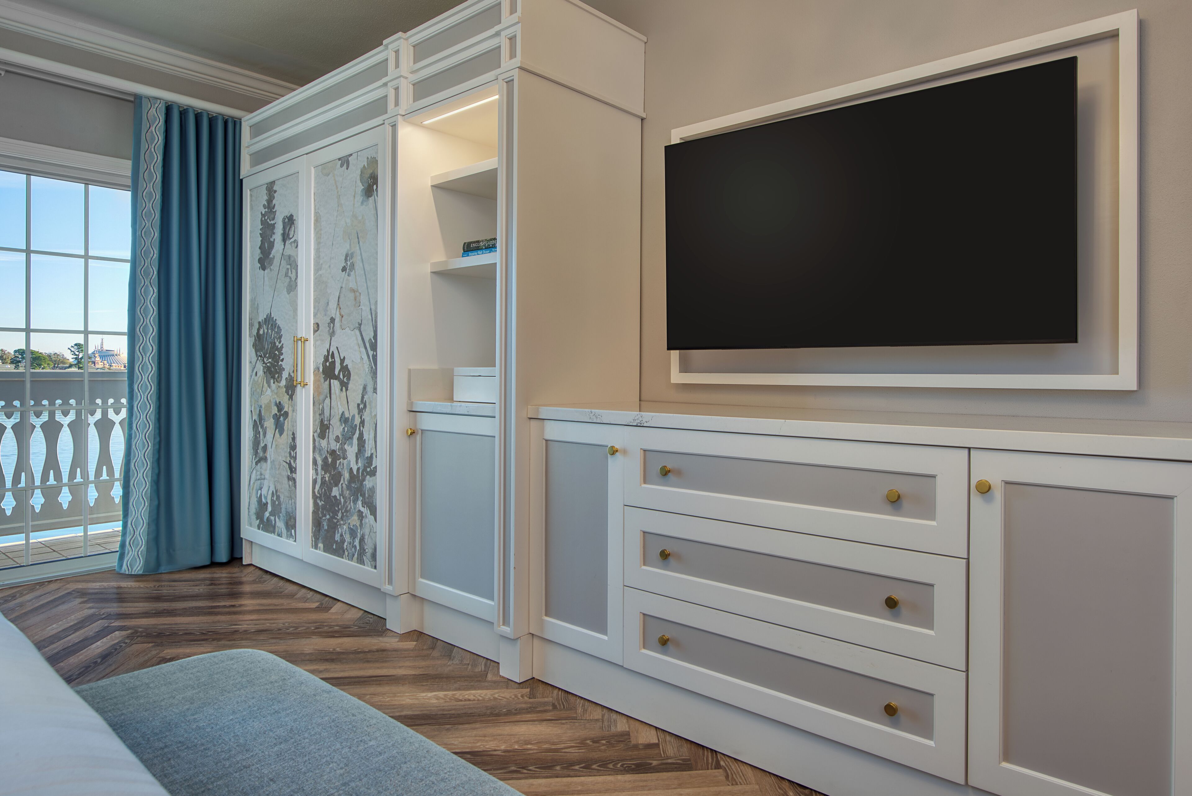 Ein Schlafzimmer mit einem großen Bett, einem an der Wand montierten Fernseher und einem Fenster mit Vorhängen.