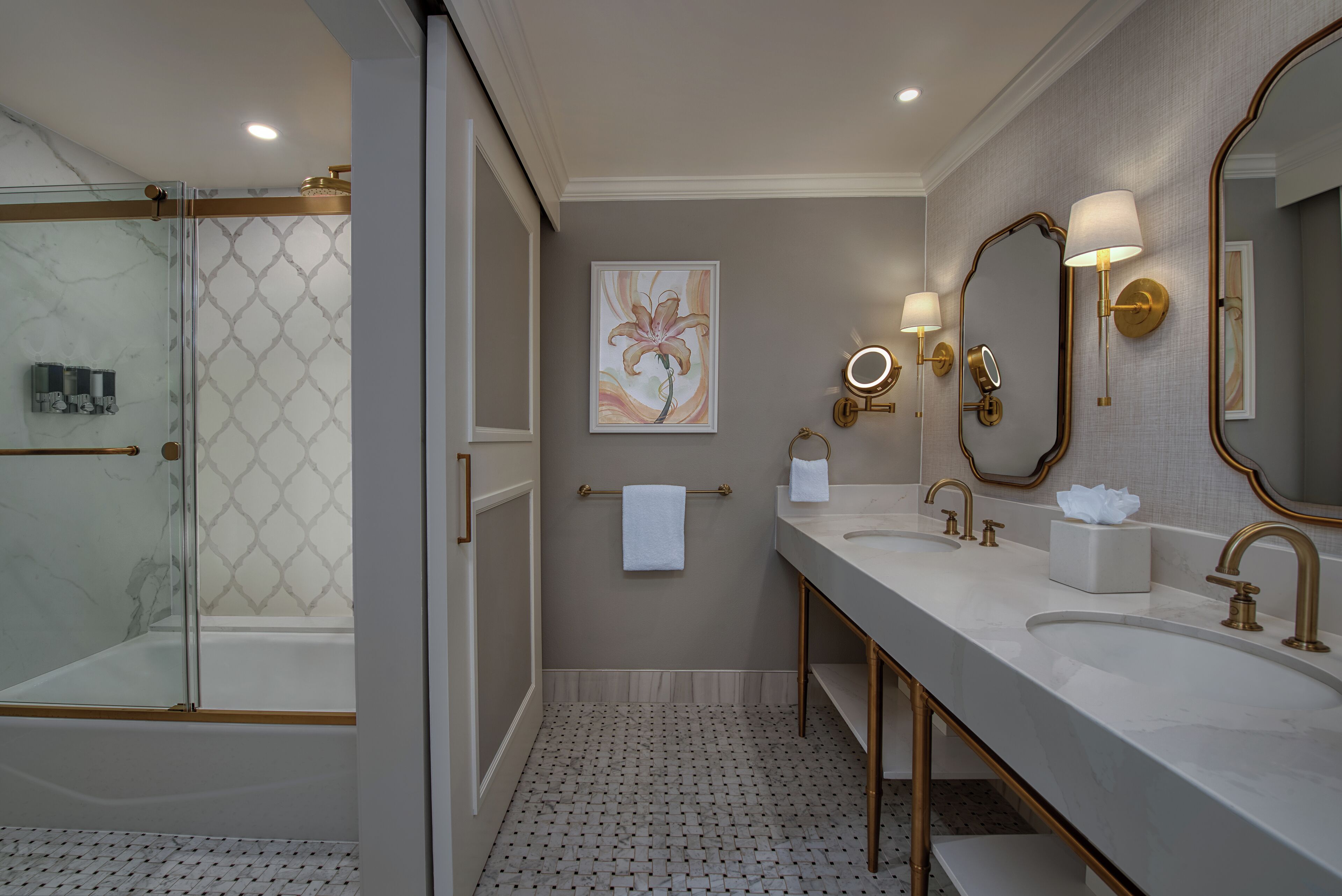Une salle de bain moderne avec une douche à parois de verre, un grand miroir, deux lavabos et un porte-serviettes.