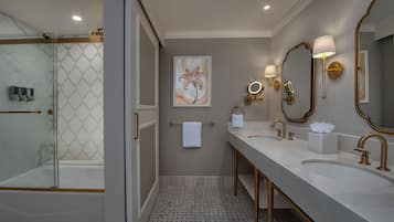 Une salle de bain moderne avec une douche à parois de verre, un grand miroir, deux lavabos et un porte-serviettes.