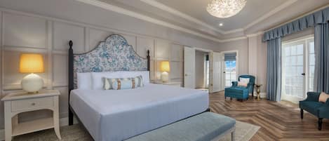 A spacious bedroom with a large bed, bedside lamps, a bench, and a chandelier.