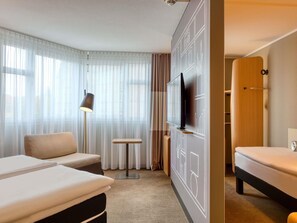 A hotel room with two beds, a TV, a lamp, a small table, and a wardrobe. - ibis Nuernberg City am Plaerrer (Nuremberg)