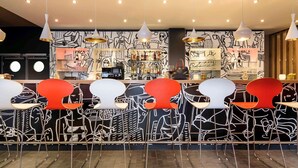 A bar area with a counter, bar stools, and hanging pendant lights. - ibis Nuernberg City am Plaerrer (Nuremberg)