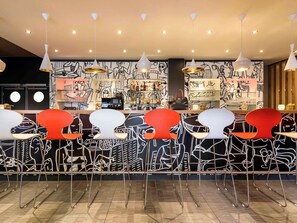 A bar area with a counter, bar stools, and hanging pendant lights. - ibis Nuernberg City am Plaerrer (Nuremberg)