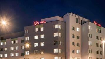 Un edificio hotel con diverse altezze, con insegna 'ibis HOTEL', numerose finestre e facciata piatta.