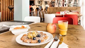 A breakfast setting with pancakes, an apple, blueberries, and orange juice on a wooden table. - ibis Nuernberg City am Plaerrer (Nuremberg)