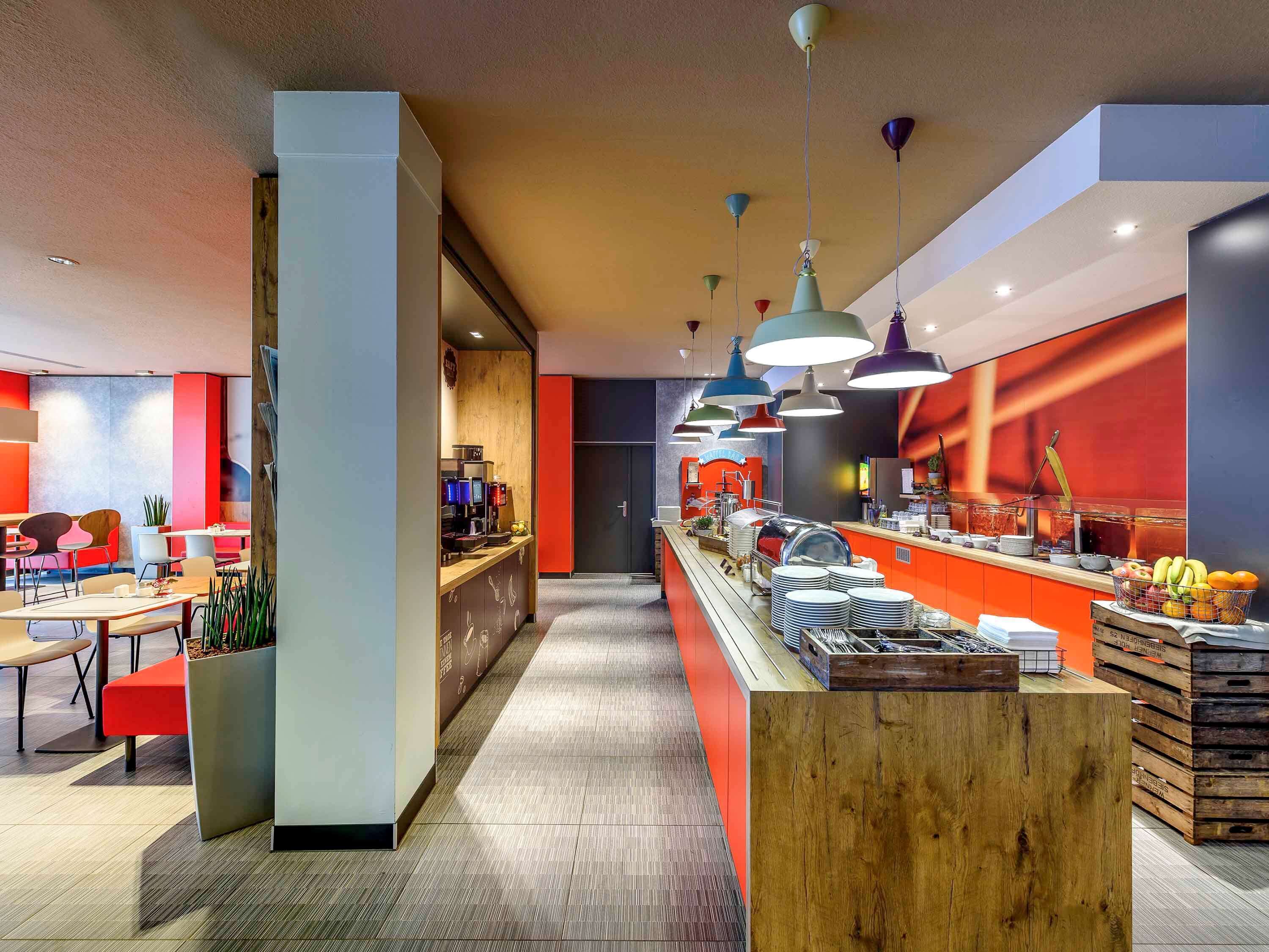 A modern cafe with a long counter, seating area, and a visible kitchen.