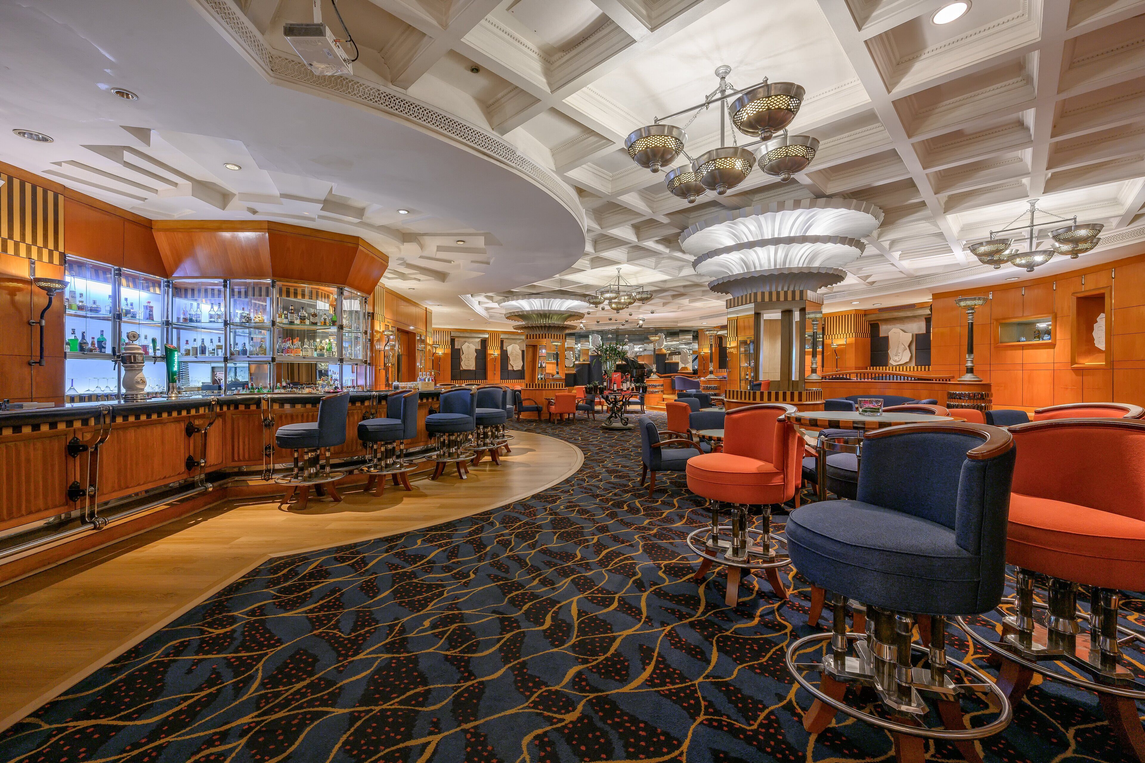 A hotel lobby with a bar area, seating arrangements, and a patterned carpet.