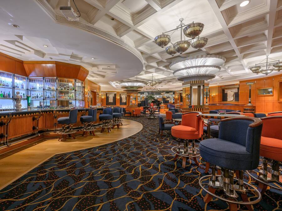 A hotel lobby with a bar area, seating arrangements, and a patterned carpet.