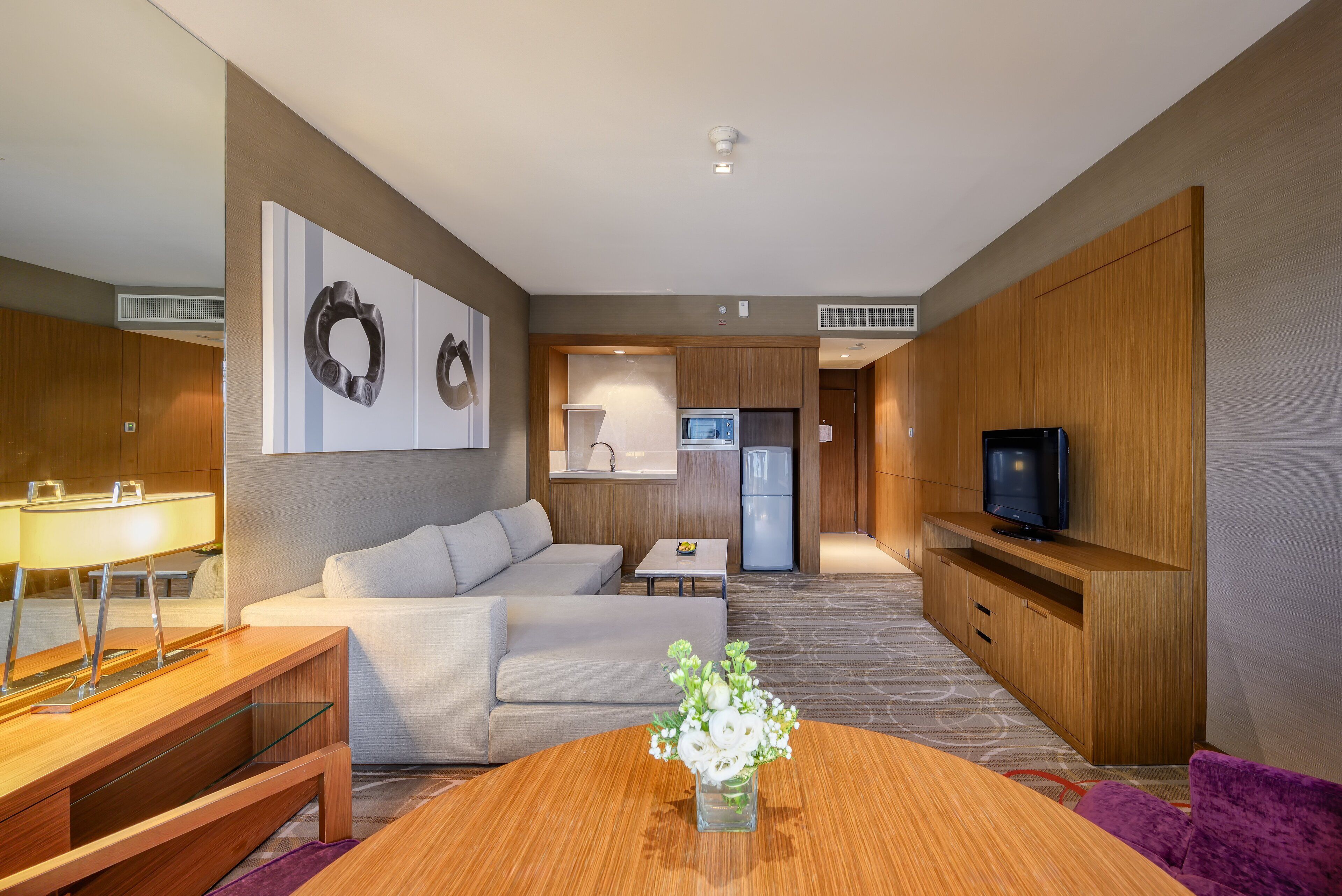 Habitació d'hotel moderna amb zona de seients, petita cuina i televisió.