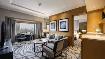 Una habitación de hotel con un ventanal grande, un sofá, una mesita de café, un escritorio y una cama.