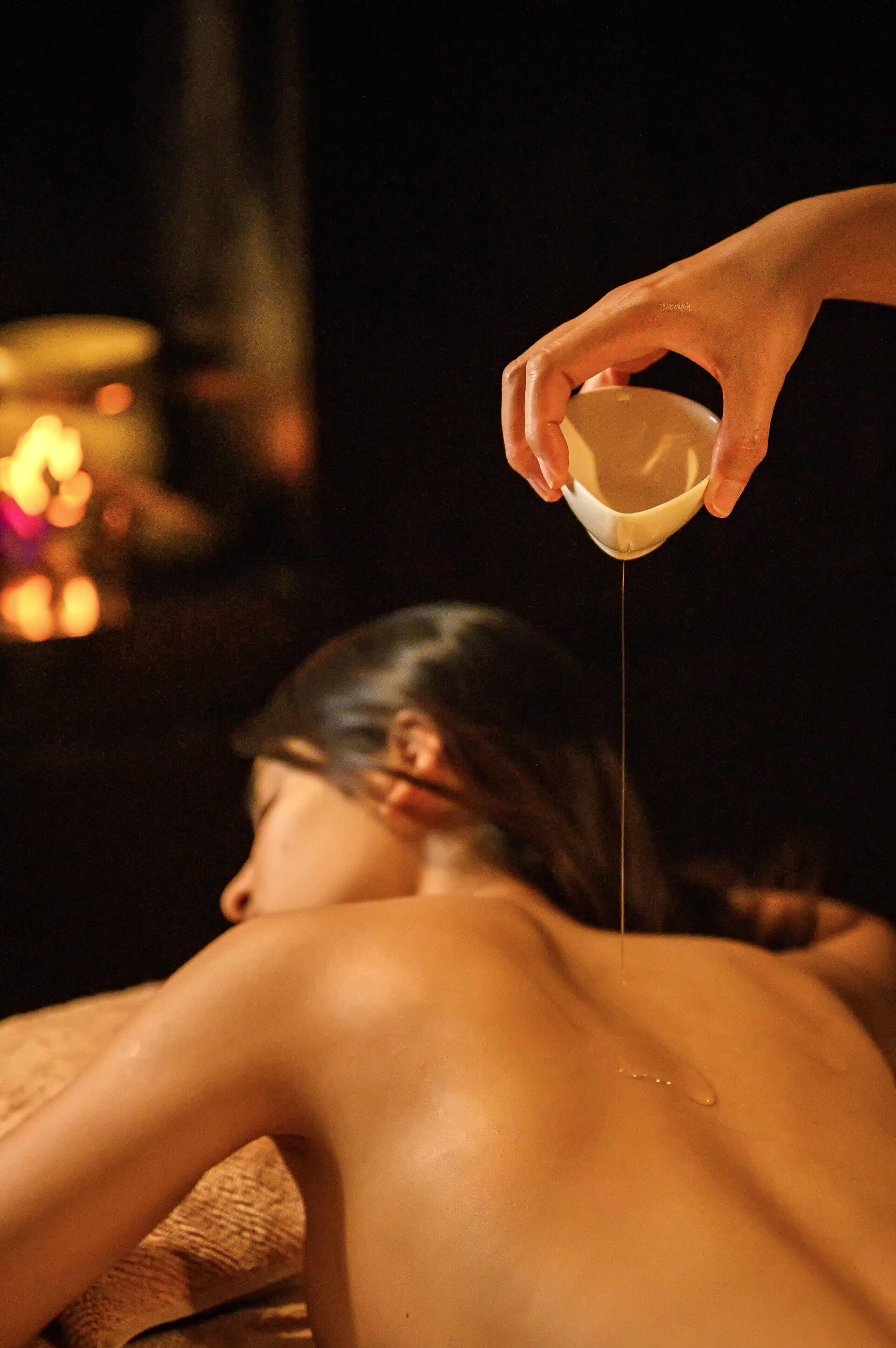 Una persona recibiendo un masaje, con una mano aplicando aceite en la espalda.