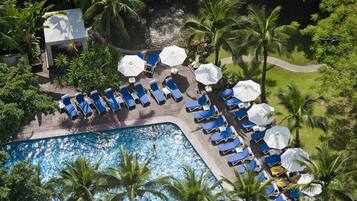 An aerial view of a resort with a swimming pool, sun loungers, and palm trees.