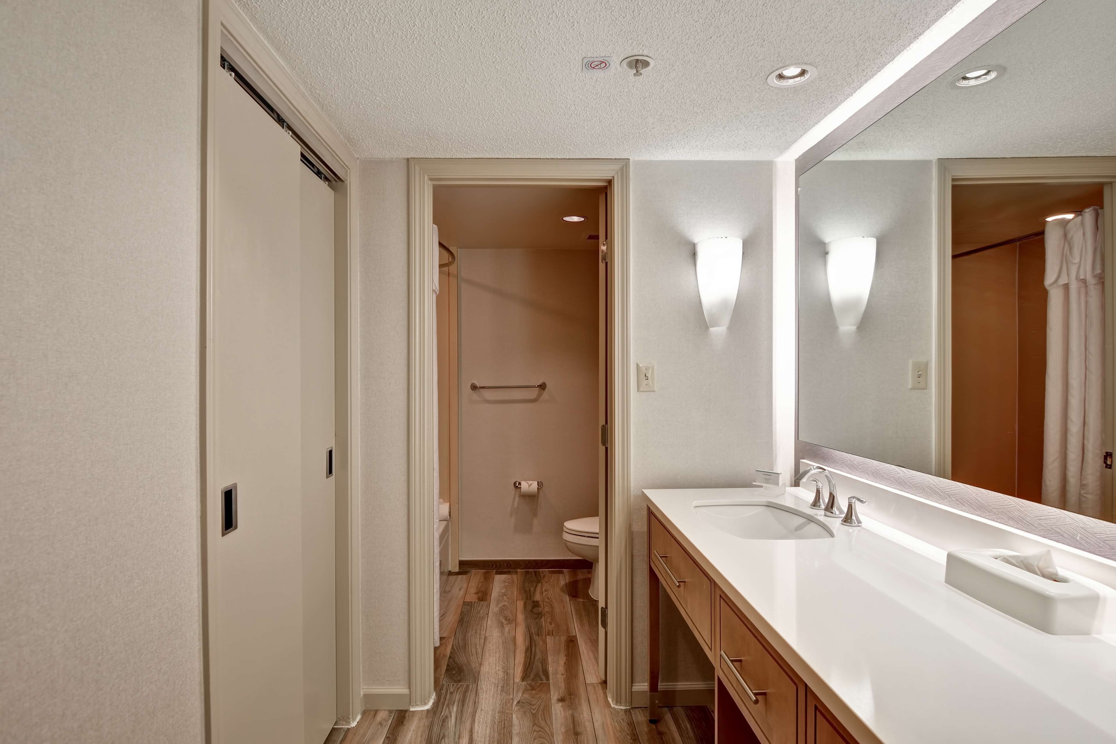 A modern bathroom with a double sink, a large mirror, and a wooden vanity.