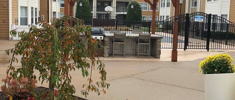 A covered outdoor area with a barbecue grill, seating, and a basketball hoop.