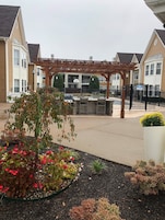 A covered outdoor area with a barbecue grill, seating, and a basketball hoop.