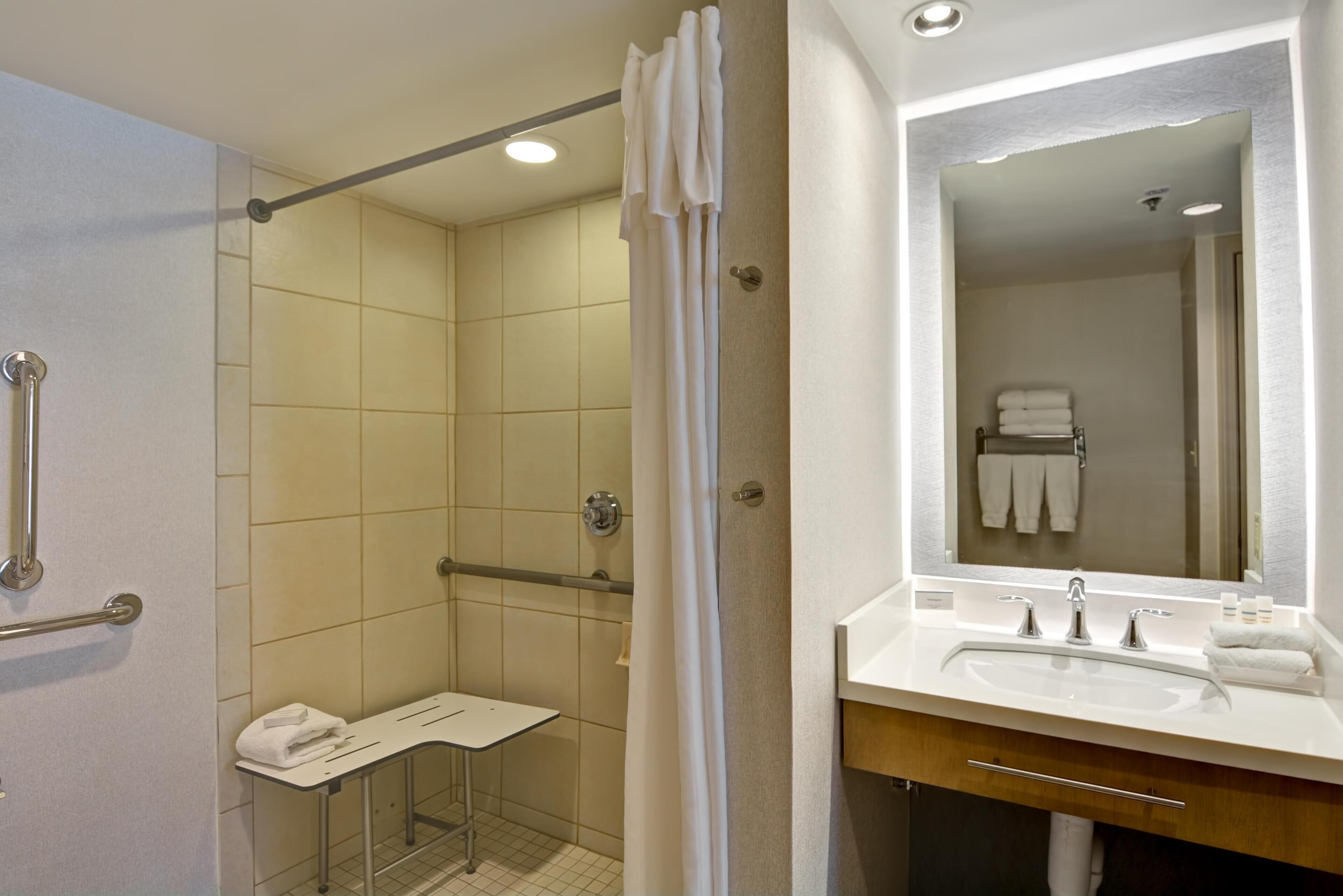 Une salle de bain équipée d’une douche, d’un lavabo, d’un miroir et d’un porte-serviettes.