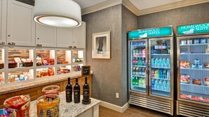 Een hotelkeuken met een marmeren aanrechtblad, een hanglamp en twee koelkasten met de tekst 'Homewood Suites by Hilton'.